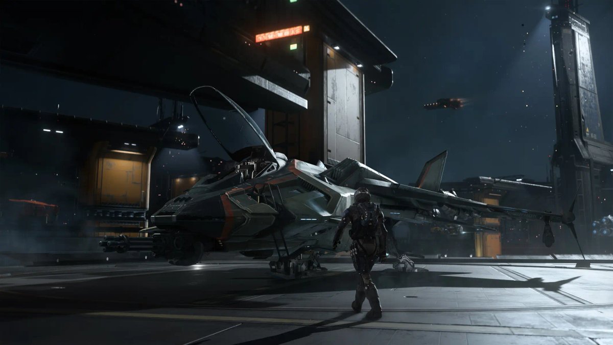Un pilota in piedi accanto a un caccia stellare grigio dalle linee affusolate sul ponte di un hangar di una stazione spaziale futuristica in Squadron 42.